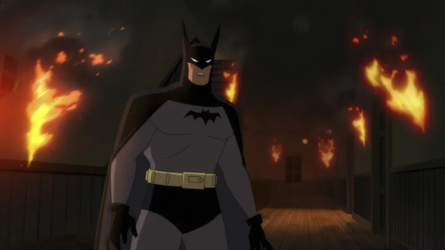 Batman standing on a wooden rooftop walkway surrounded by fire in Batman: Caped Crusader