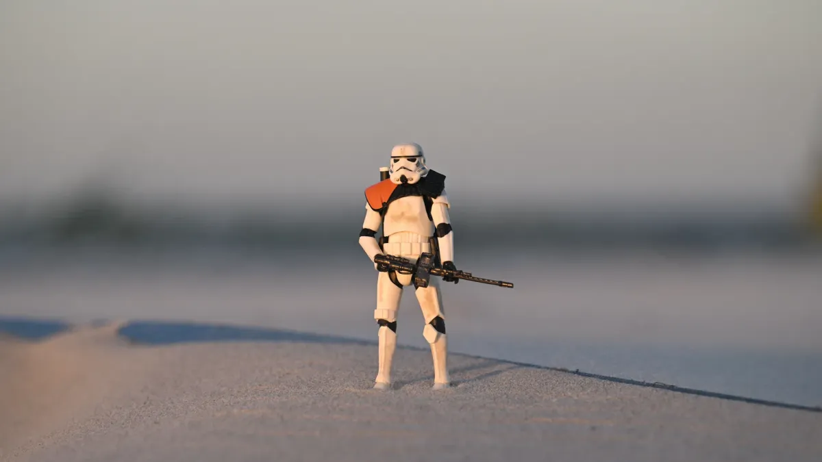 The Sandtrooper standing on the sharp edge of a sand dune ridge against the twilight sky