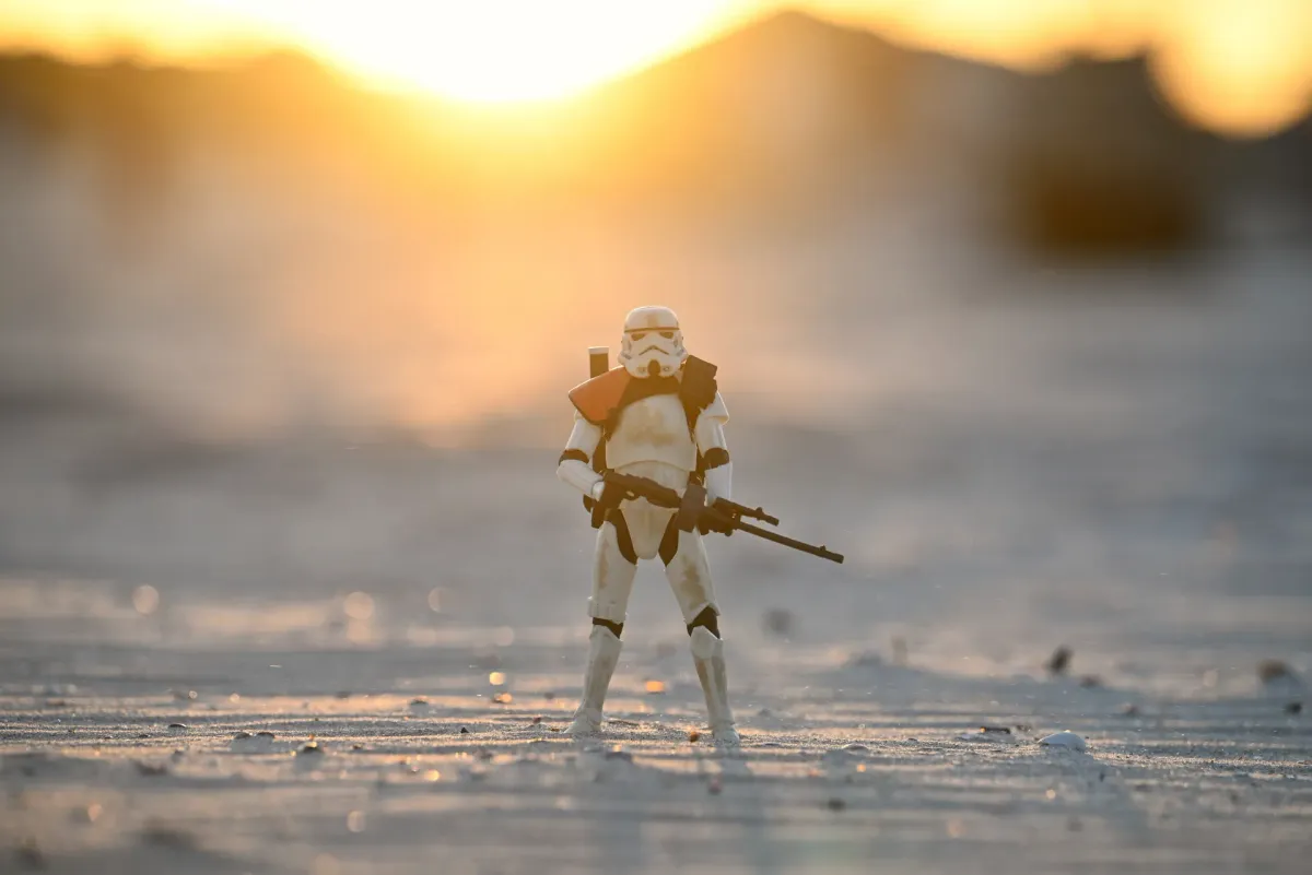 Backlit silhouette of an action figure against twilight sky on coastal beach