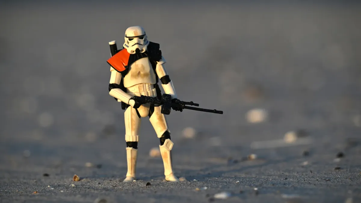 Hasbro Black Series Sandtrooper standing on dark sand flat illuminated by low raking side light