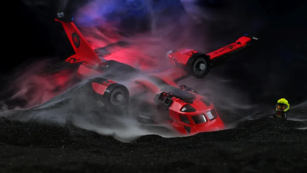 The LEGO City Fire Rescue Plane (60413) resting on black slag in dramatic smoke with a firefighter minifigure in yellow helmet watching
