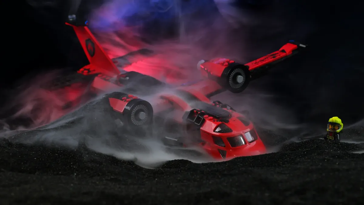 The LEGO City Fire Rescue Plane (60413) crash-landed in black slag with thick dramatic smoke swirling and a firefighter watching in the fog