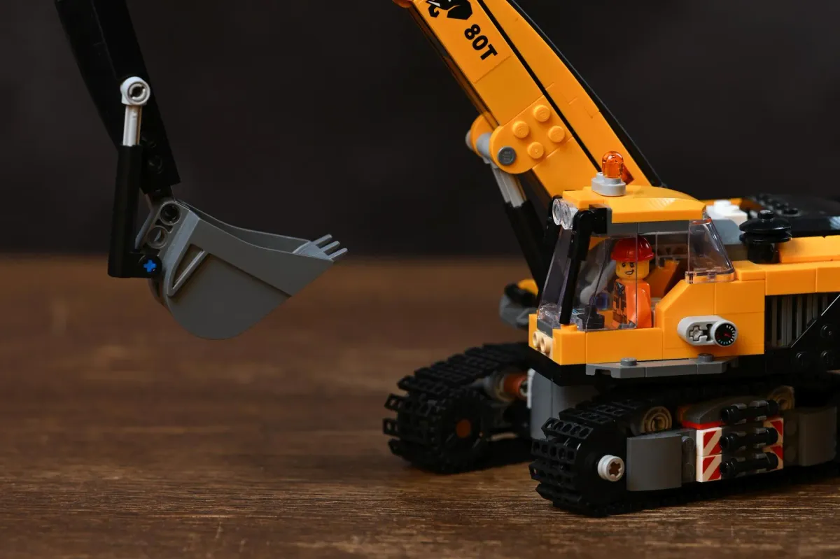 Close-up of the LEGO City Yellow Construction Excavator (60420) showing the chain track detail and boom arm assembly