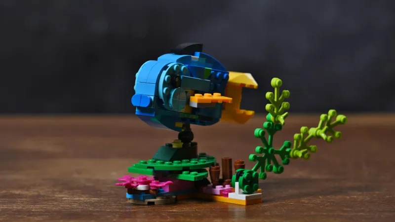 The blue-and-yellow fish alternate build of the LEGO Creator Exotic Parrot (31136) set on its seabed stand with sea plants