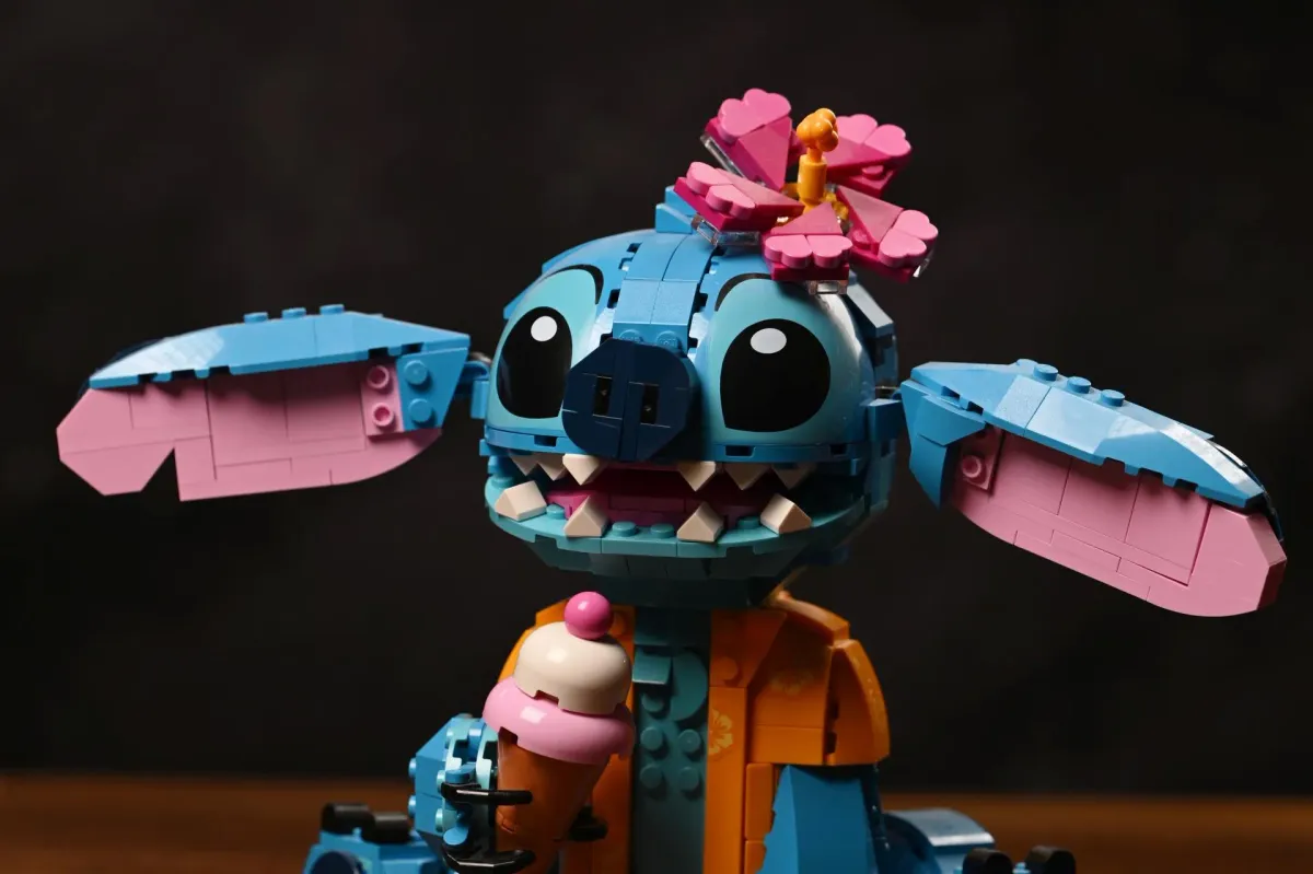 The LEGO Disney Stitch (43249) build with both ears tilted fully outward, showing the orange jacket detailing and flower accessory