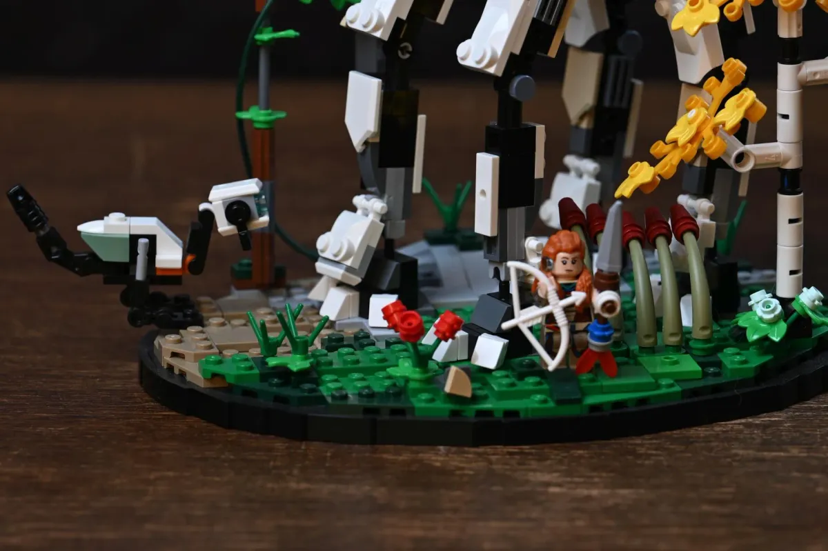 Detail shot of the LEGO Tallneck's scenic base, showing Aloy, the birch tree subassembly and the small Watcher machine among the foliage