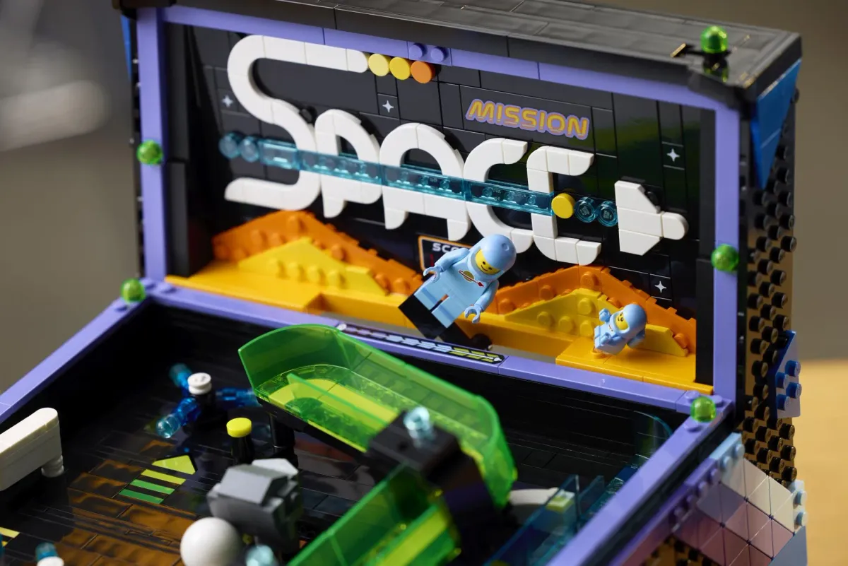 Close-up of the LEGO Icons Arcade Pinball Machine backboard showing the classic space astronaut and baby astronaut minifigures against a retro Mission Space design