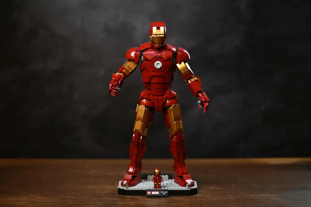 The fully built LEGO Iron Man Mark 3 Collectors' Edition (76344) standing on its display base with the exclusive minifigure at its feet, photographed against a dark background