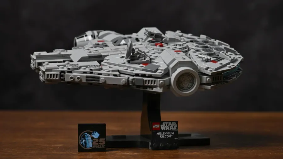 The finished LEGO Millennium Falcon (75375) mounted on its display stand, with the Millennium Falcon nameplate and 25th-anniversary R2-D2 tile beside it