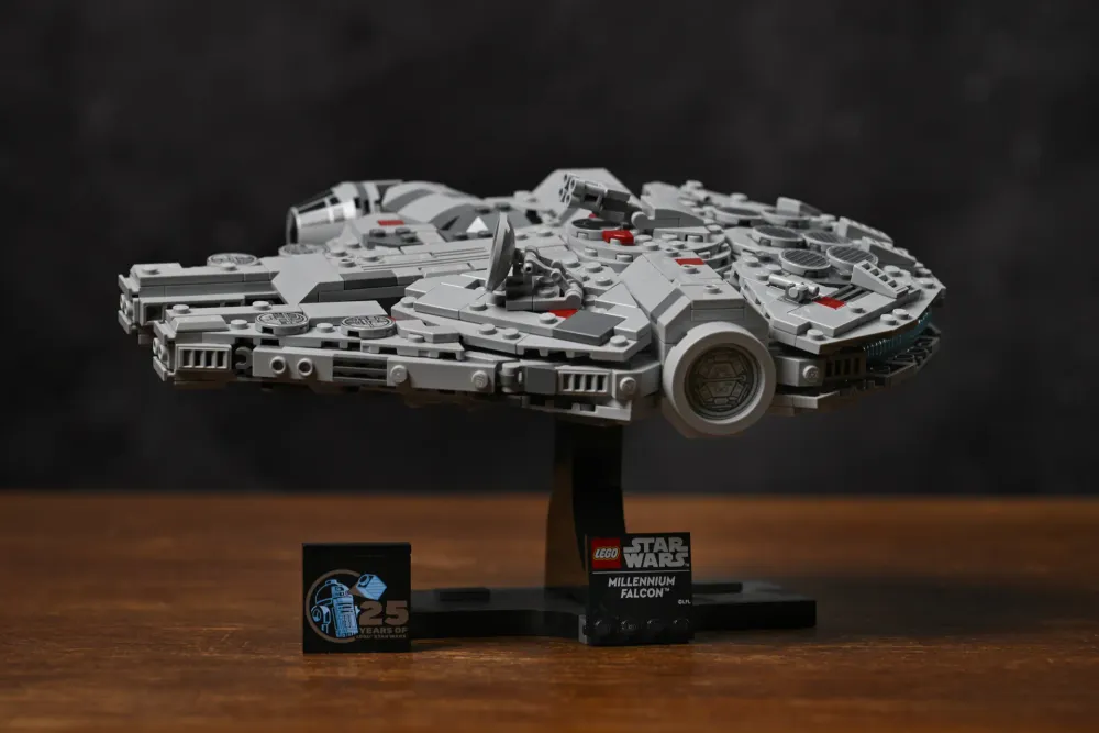 The finished LEGO Millennium Falcon (75375) mounted on its display stand, with the Millennium Falcon nameplate and 25th-anniversary R2-D2 tile beside it