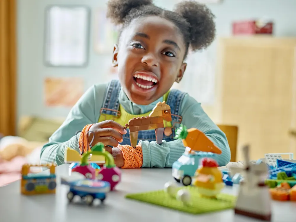 A girl laughing while building a LEGO horse - official LEGO lifestyle photo