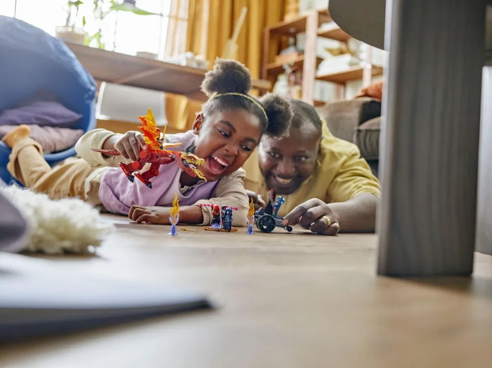 Parent and child playing with LEGO NINJAGO sets on the floor - official LEGO lifestyle photo