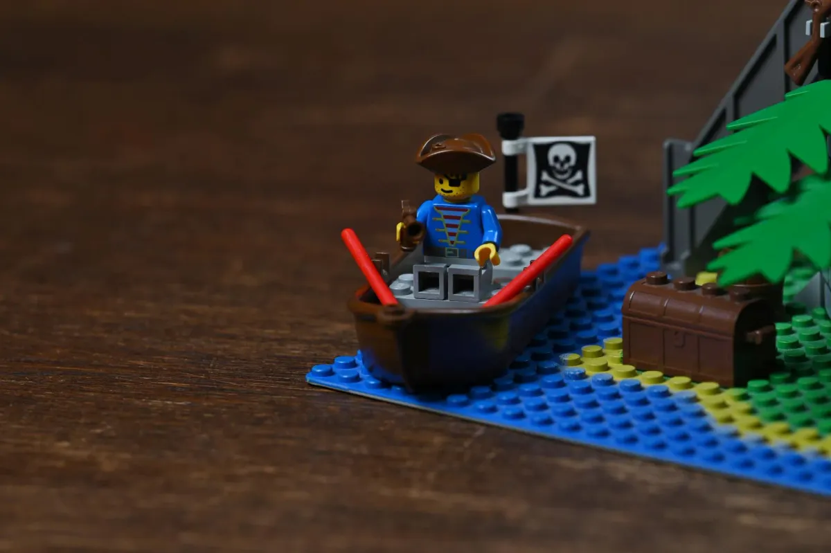 Close-up of the LEGO Pirates Forbidden Island (6270) rowboat, with a pirate captain minifigure, oars, treasure chest, and Jolly Roger flag