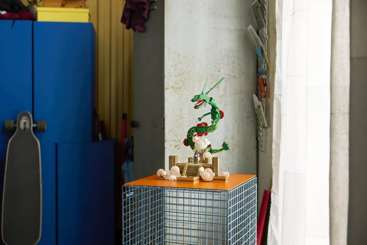 The LEGO Rayquaza set displayed on a pedestal in a living space, showing the full Sky Pillar diorama base with clouds and staircase