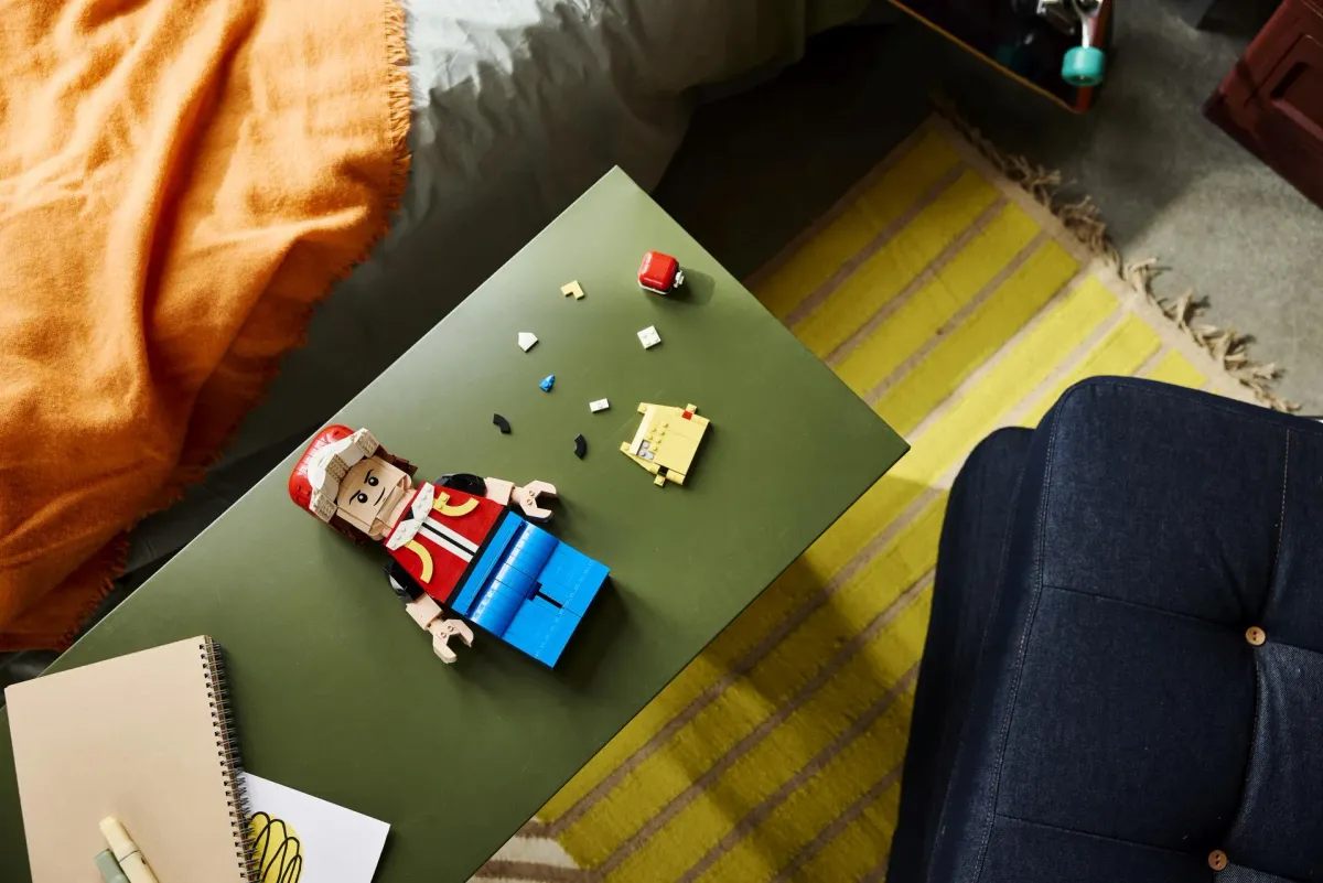 The LEGO Up-Scaled Red Minifigure mid-build lying on a table, with the torso assembled and the yellow head section still in separate parts
