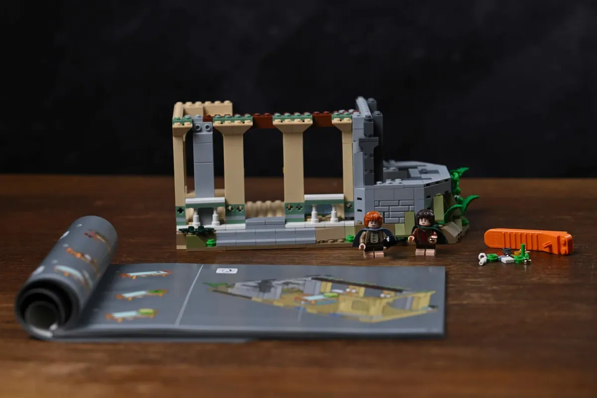 The first completed section of the LEGO Rivendell (10316) build on a wooden table, next to the open instruction booklet, spare parts and the LEGO building tool
