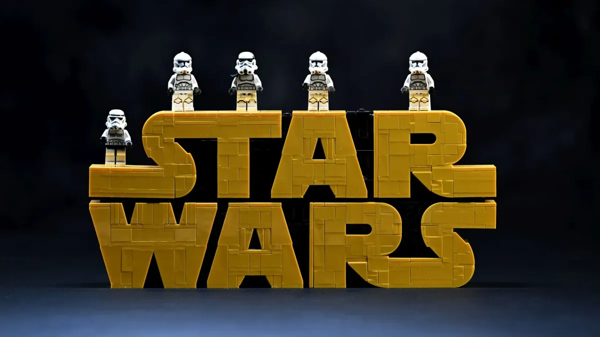 Five LEGO Stormtrooper and Clone Trooper minifigures from an existing collection lined up on top of the LEGO Star Wars Brick-Built Logo (75407)