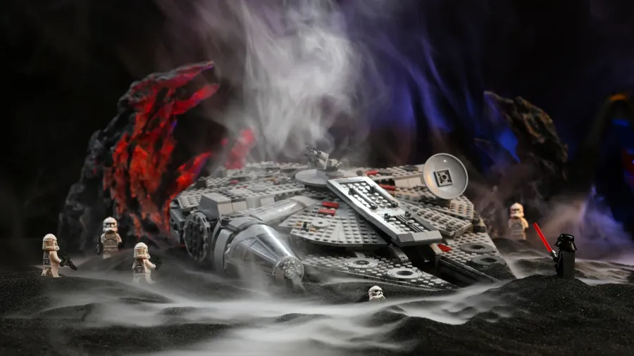 The LEGO Star Wars Millennium Falcon (75257) surrounded by Darth Vader and clone troopers in thick pooling fog and colored backlight on our black slag diorama stage