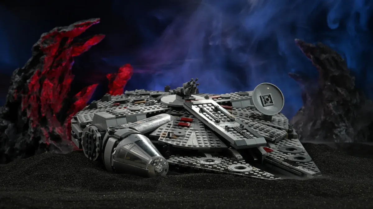 The LEGO Millennium Falcon (75257) resting on the black slag diorama stage with blue backdrop haze and red rock rim light