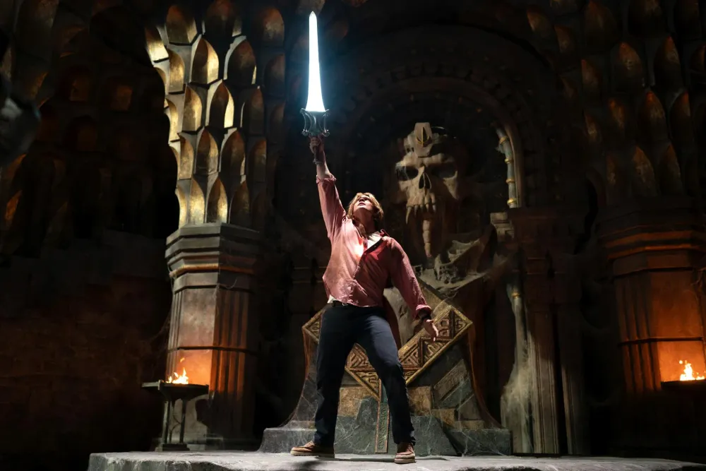 Nicholas Galitzine as Adam raising the glowing Sword of Power inside Castle Grayskull in Masters of the Universe (2026)