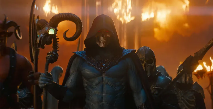 Jared Leto as a hooded Skeletor holding a ram-headed staff in front of a wall of fire