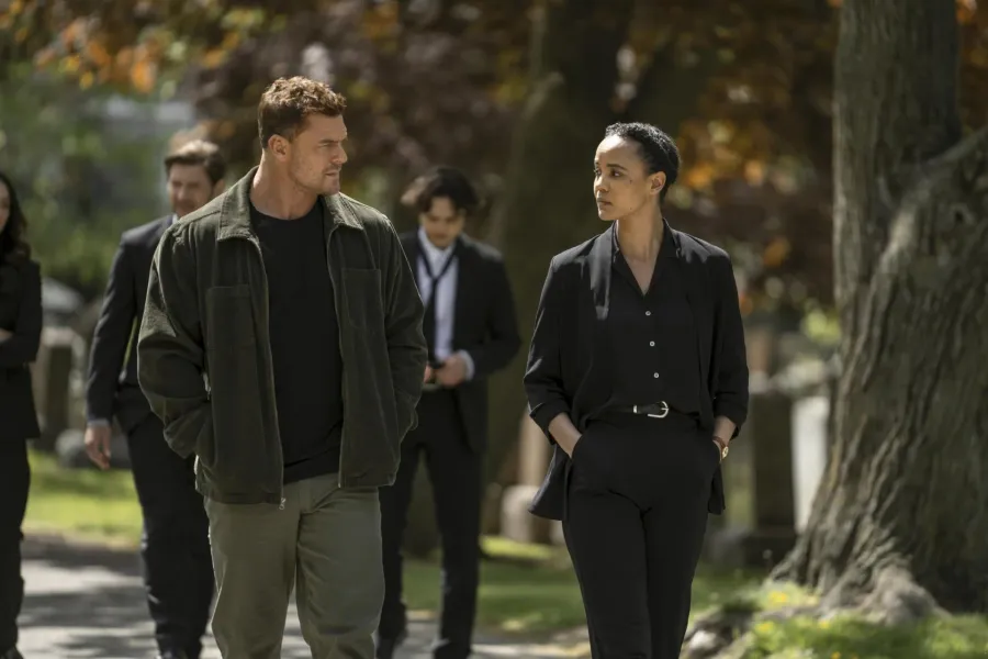 Maria Sten as Frances Neagley walking a cemetery path alongside Alan Ritchson as Jack Reacher