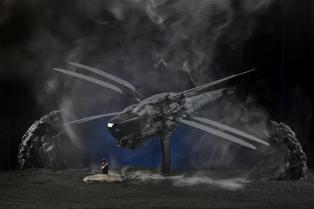 A LEGO Dune ornithopter model hovering over black volcanic terrain, wrapped in thick drifting smoke from the PMI SmokeNINJA fog machine