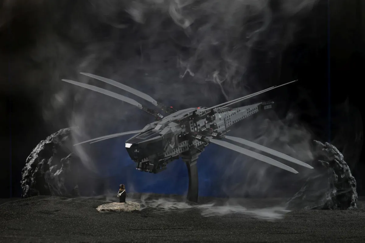 A LEGO Dune ornithopter model hovering over black volcanic terrain, wrapped in thick drifting smoke from the PMI SmokeNINJA fog machine