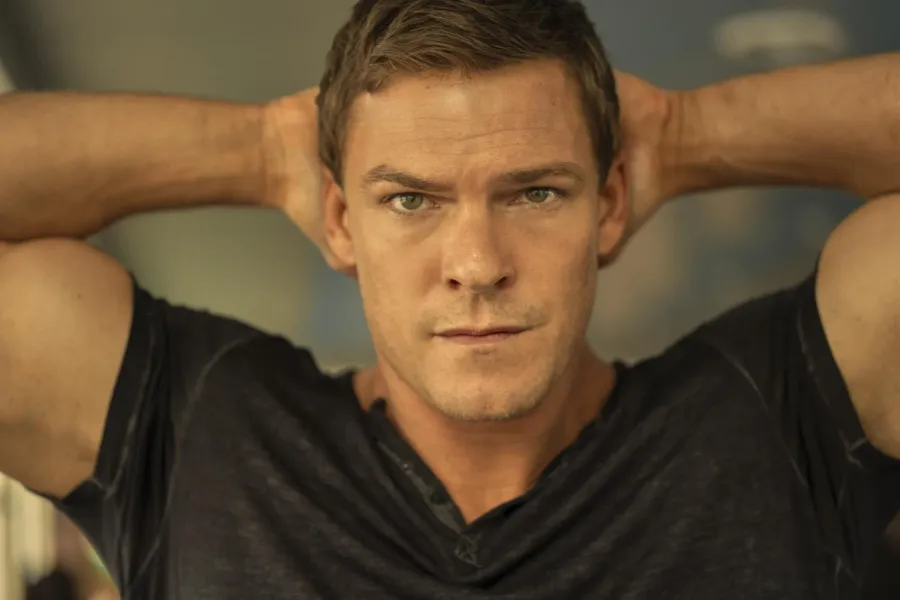 Close portrait of Alan Ritchson as Jack Reacher with his hands laced behind his head