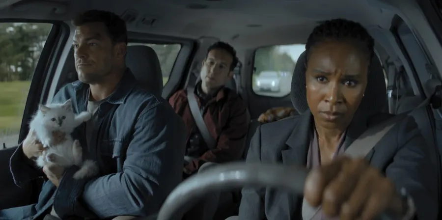 Alan Ritchson as Jack Reacher holding a rescued kitten in the front seat of a car with two wary allies in Reacher season 4