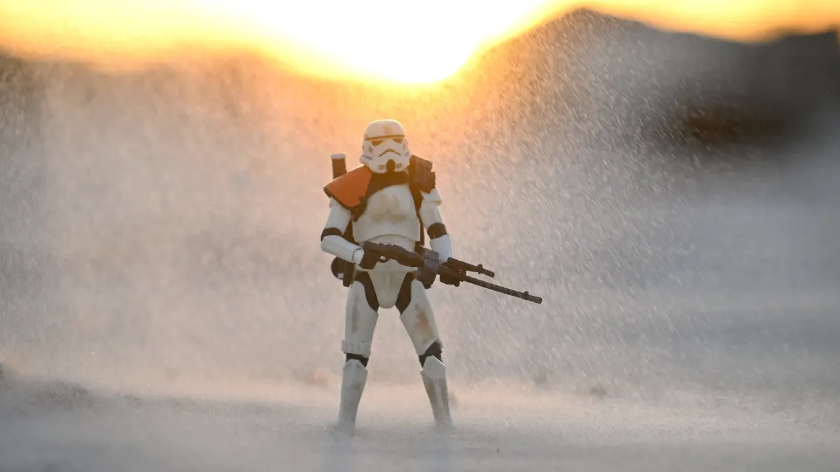 Action figure in an epic swirling sandstorm with backlit dust particles and the setting sun behind