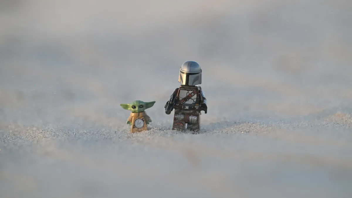 LEGO The Mandalorian and Grogu minifigures trekking across desert dunes under warm evening light